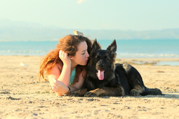 Urlauberin in Spanien am Strand küsst Ihren Hund
